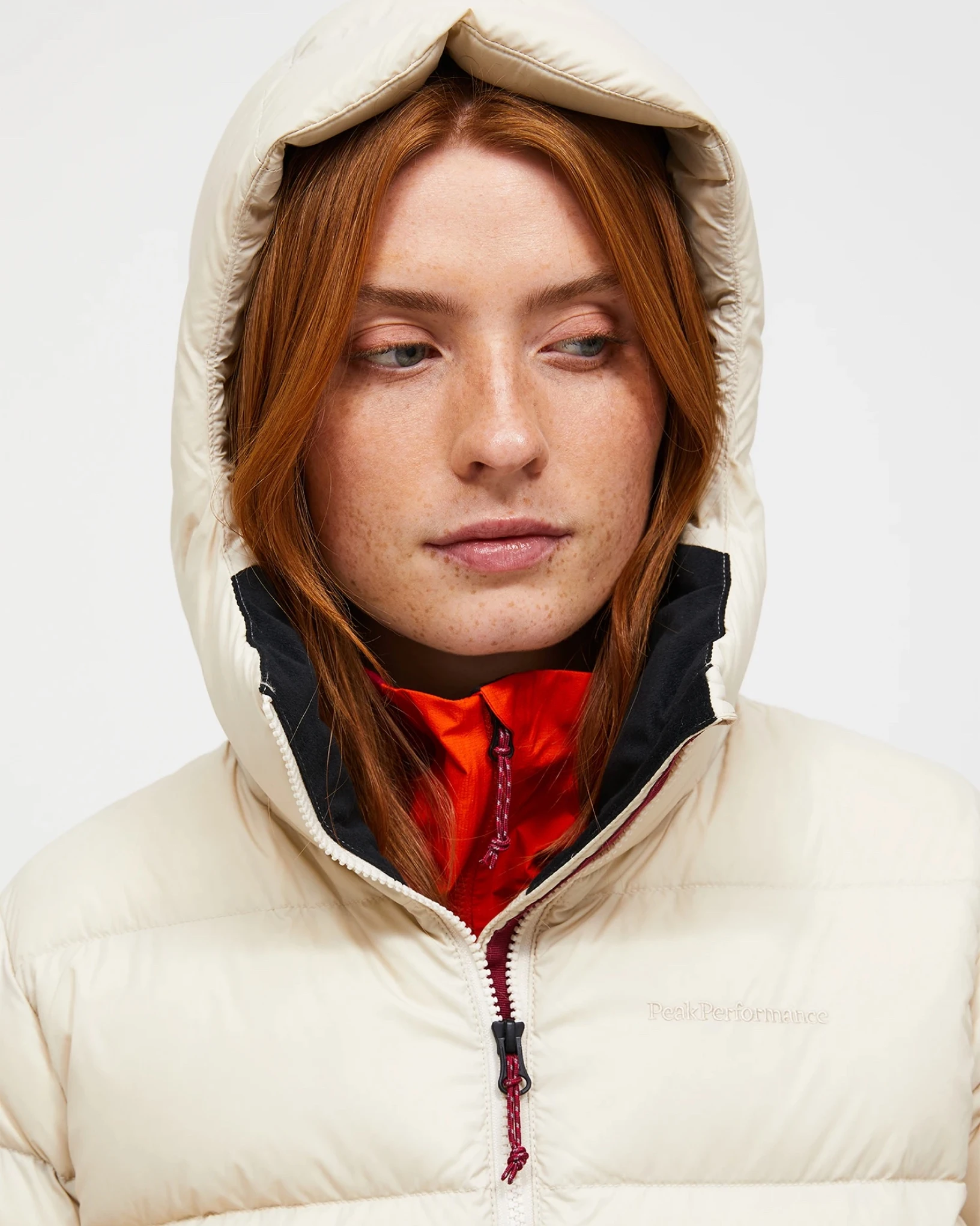 Close view of a skier in a cream down jacket with the hood up
