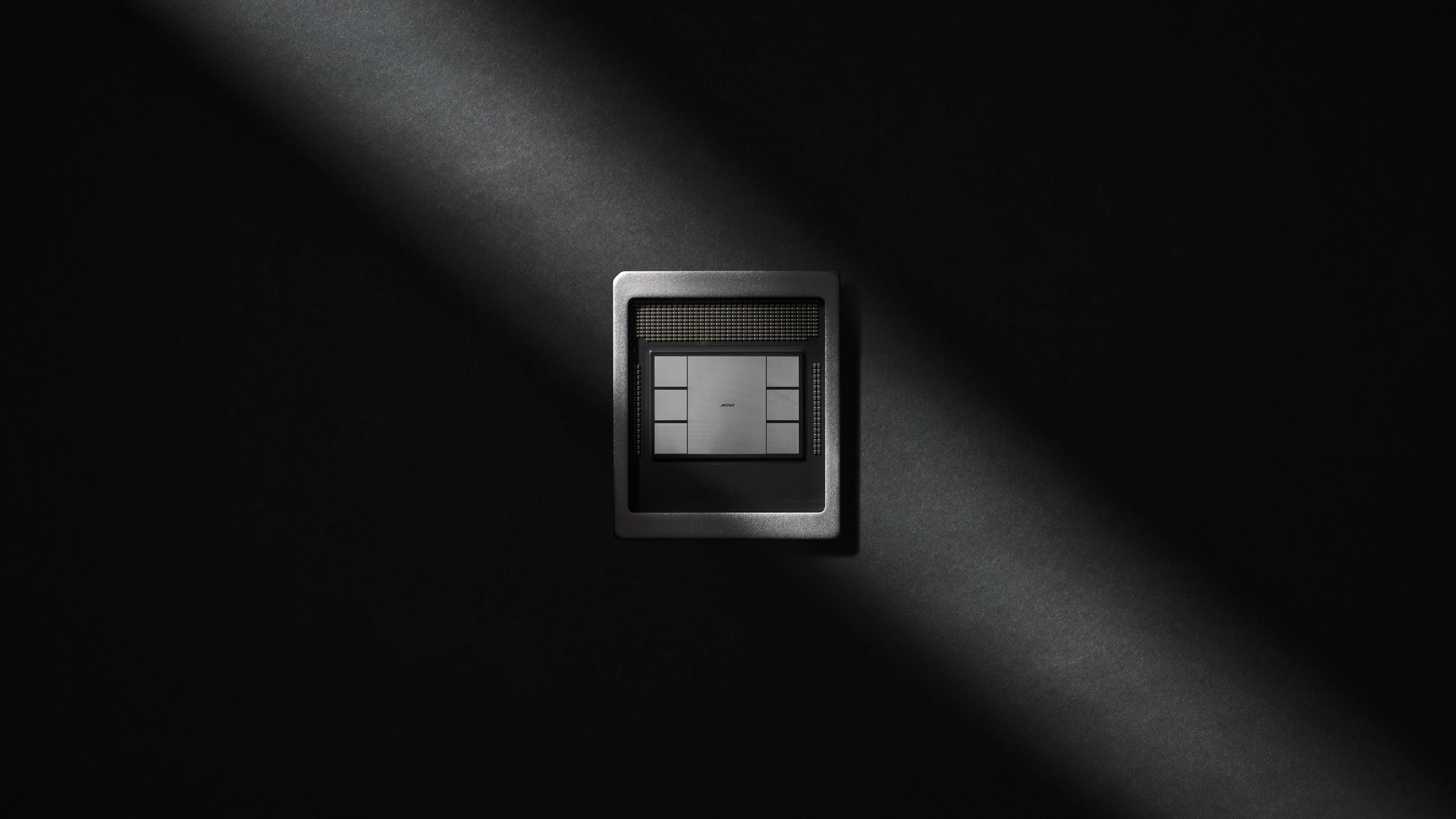 Etched chip on a dark background crossed by a single shaft of light
