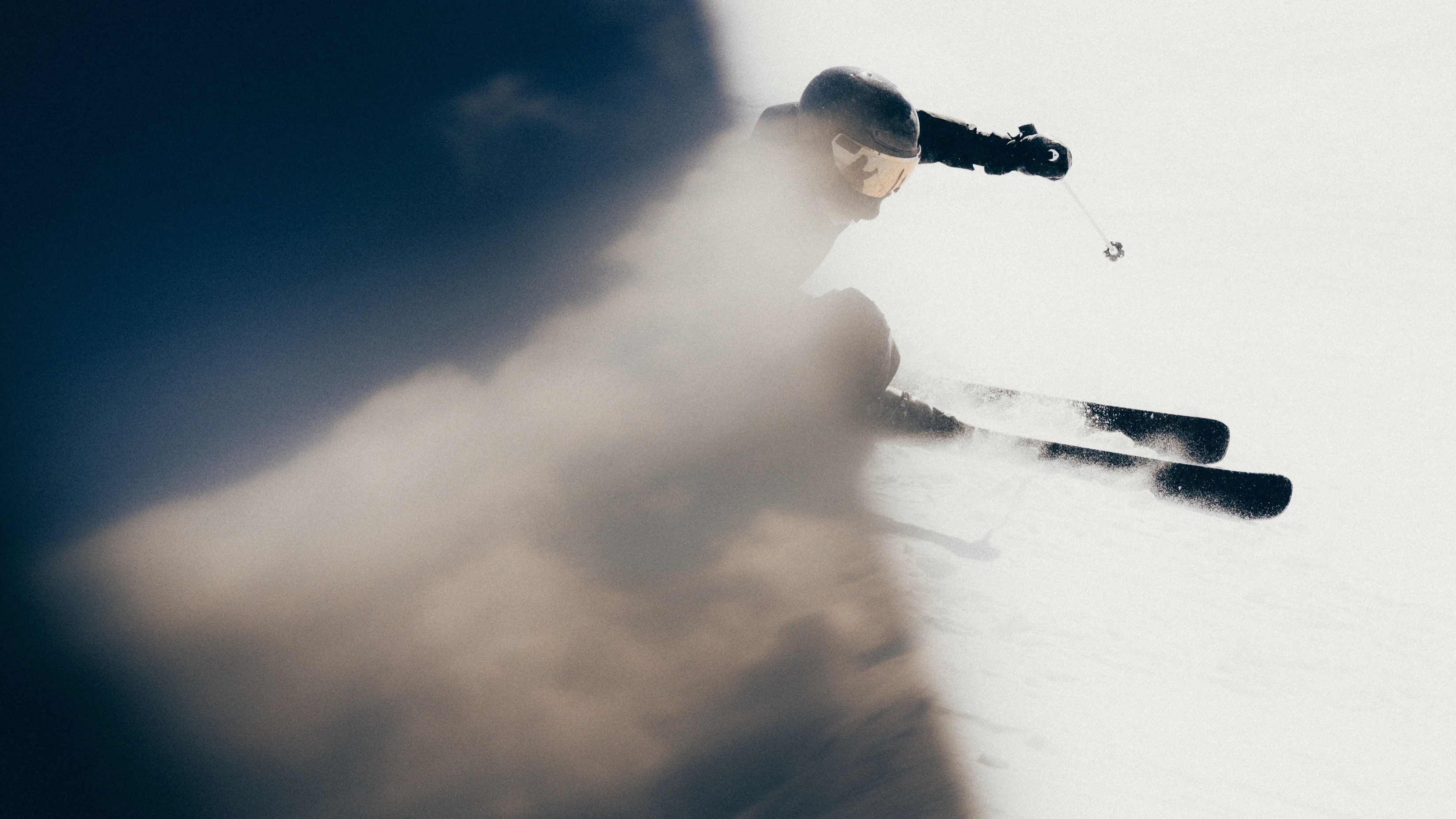 A skier carving through spray on Atomic Volant skis